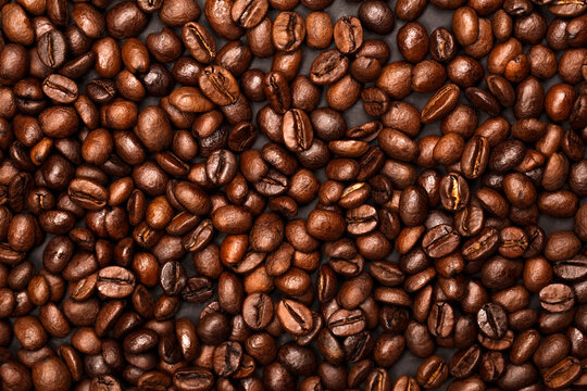Full frame background of roasted arabica coffee beans with rich glossy texture. Specialty third wave coffee for roastery design.