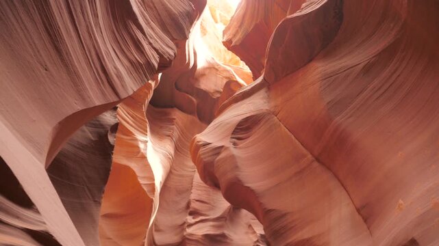 Sunlight illuminating the smooth curving sandstone walls inside antelope canyon, revealing natural geological erosion patterns and rich red orange textures in page, arizona