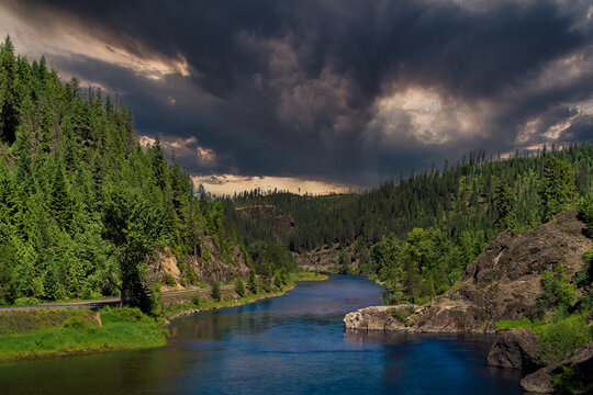 THE ST JOE RIVER OUTSIDE OF AVERY IDAHO WITH LUSG GREEN TREES AND FOLIAGE WITH A DARK STORMY SKY 