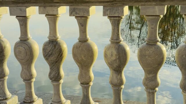 Marble balusters stand along a lakeside railing glowing in soft sunlight. A serene autumn view in Catherine Park, Pushkin, Russia inspires quiet wonder and peace.