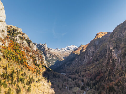 Alpine valley landscape in autumn with snow capped peak at the end of a glacial gorge, Val di Mello, Lombardy, Italy