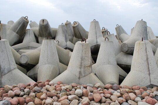 Row of concrete tetrapods on a breakwater with boulders and sky