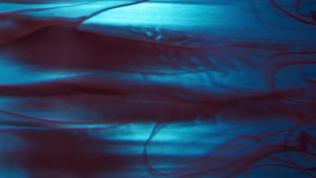 Vertical video. Flowing paint. Mist swirling. Defocused blue maroon red colorful water acrylic drip fluid vapor wave floating on abstract art background.