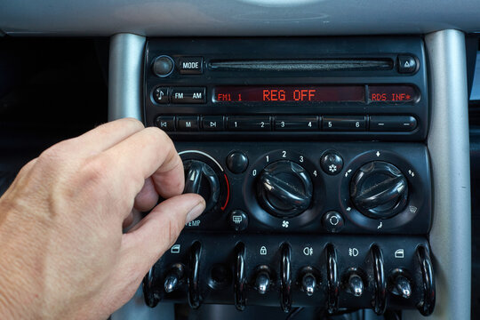 Hand adjusting car stereo volume and radio controls