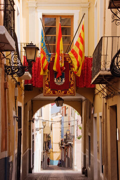 Archway with flags over narrow pedestrian street joiosa, alicante