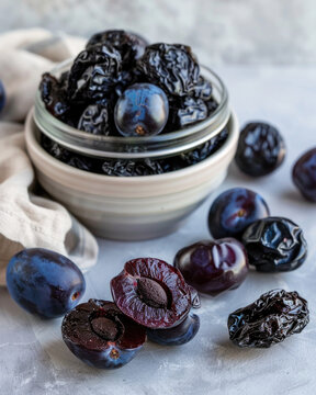Rustic food photography of dried plums and fresh plums, prunes spilling from a glass jar