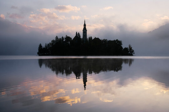 Church of assumption silhouetted on lake bled island at sunrise