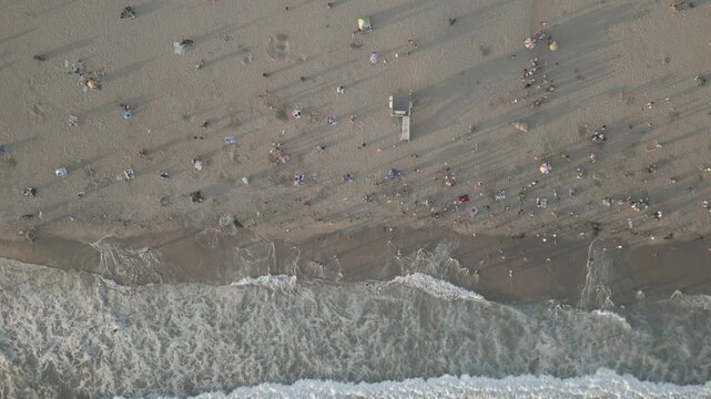 Top down aerial of ocean waves on a sandy beach in Santa Monica