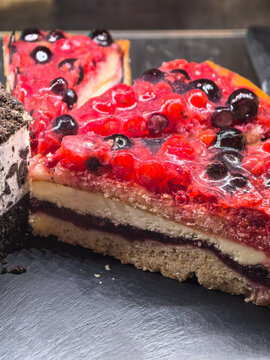 Glossy berry cake slices gleaming on a dark serving tray