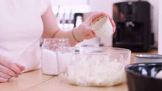 Baking process. Preparing dish. Female chef measuring ingredient adding salt sugar flour in glass bowl with cottage cheese white dough.