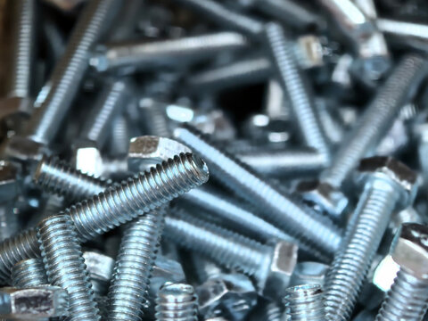 Silver machine bolts gather in a quiet industrial close-up