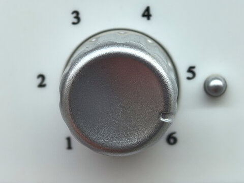 Metal dial rests between numbered settings on a white panel