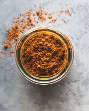 Top view professional cookbook photography of Lebanese seven spice powder (baharat), warm reddish-brown spice powder in a small glass jar, minimal elegant 