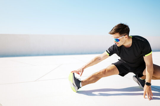 Man stretches under sunny sky before workout on a rooftop space
