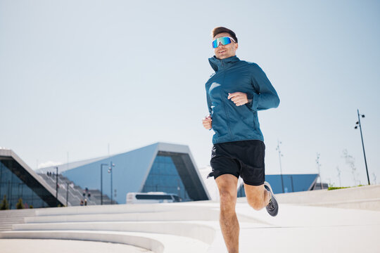 Energetic runner enjoying a sunny day near modern architectural buildings