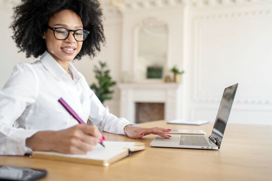 Creating ideas in a bright and stylish workspace while writing notes and using a laptop