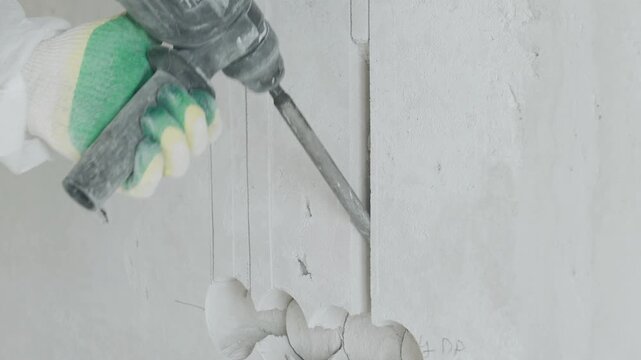 Using a rotary hammer and a special chisel, the installer efficiently chases a wall in an apartment to lay down electrical wiring, focused on precision and cleanliness throughout the process.