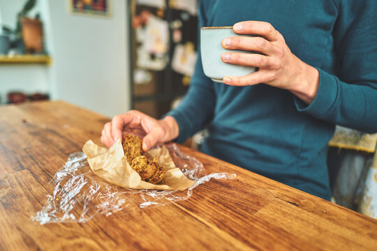 Woman Holding a Ceramic Cup and Picking Up a Piece of Cake at a Table