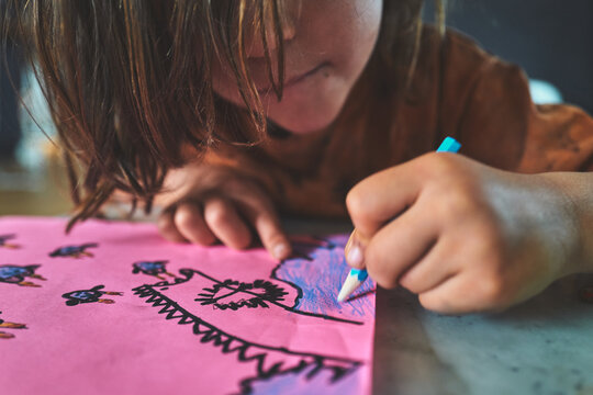 Boy Leaning Close to Color a Drawing on Pink Paper