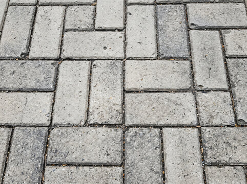 Close-up of rustic light grey concrete paving flagstone texture with geometric rectangular interlocking stone block pattern on public walkway floor surface for industrial paving design backdrop