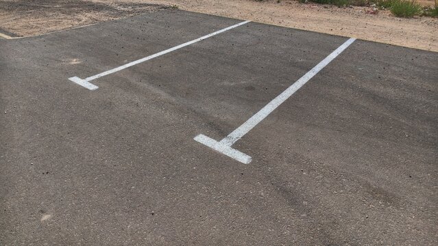 Empty parking space with white painted lines on asphalt, vacant parking spot in an outdoor car park, parking lot road markings, free spot ready for any car, available public parking in the city center