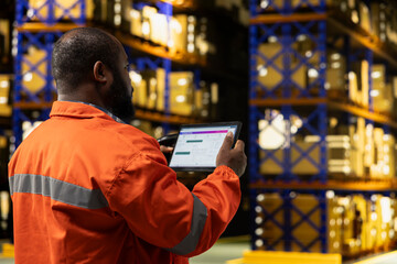 Warehouse worker, tablet and package tracking as employee checks shipment records by stocked racks. Logistics monitoring, order status and inventory control aid deliveries in distribution warehouse. © DC Studio