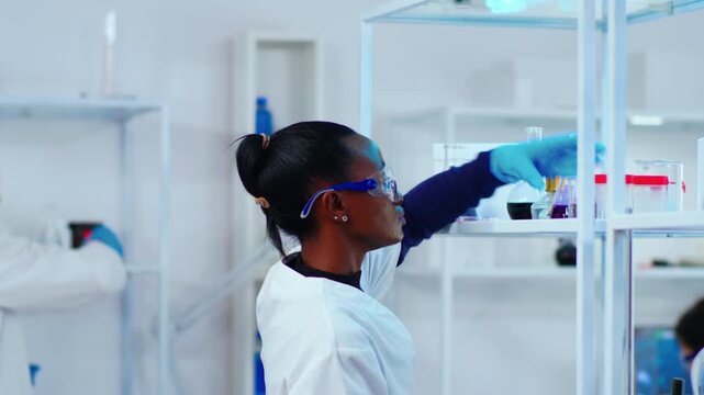 Chemist, flask and chemical research as a woman raises a glass vessel containing purple liquid for closer inspection in a laboratory, for sample analysis, quality assessment and experimental science.