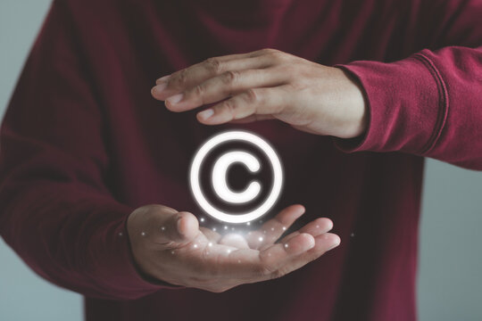 Copyright and patent protection concept featuring glowing copyright symbol held by hands, representing intellectual property rights, creative ownership, legal security, and innovation.