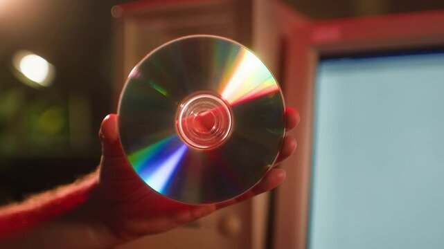 CD disc in hand, compact disc and CD ROM drive of retro desktop computer, inserting disk into old 90s PC tray, vintage data storage technology