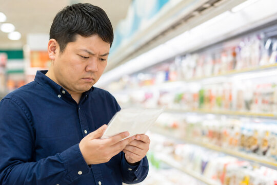 スーパーで商品の包装を読む日本人男性