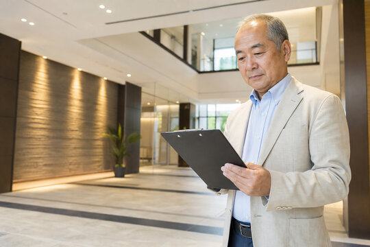 建物のロビーでクリップボードを確認する日本人男性