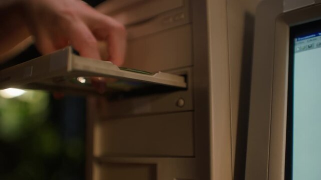 Retro computer tower close up, hand inserting floppy disk and opening CD ROM drive of old 90s desktop PC, vintage personal computer in office