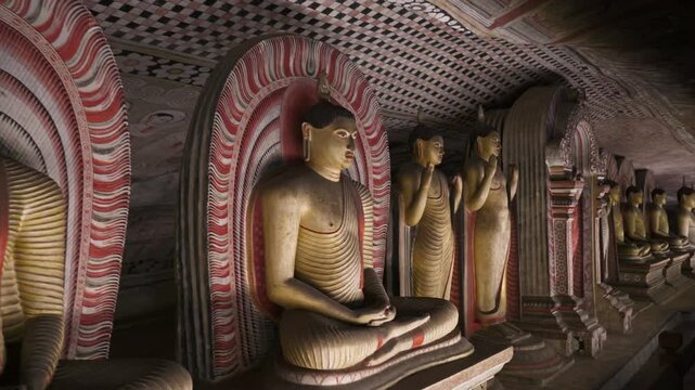 Seated and standing Buddha statues line a richly painted cave temple in Sri Lanka, with decorative niches and patterned interior surfaces.