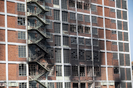A prefabricated apartment building with a charred facade and broken windows.
