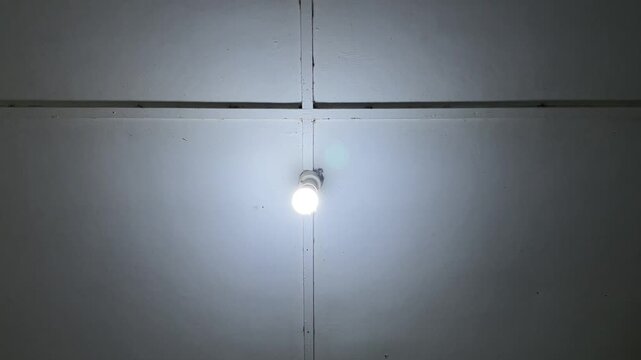 Low angle shot of a ceiling light bulb glowing steadily without flickering inside an indoor room.