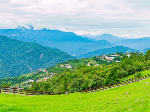 Green hillside landscape with wooden fence and distant mountains