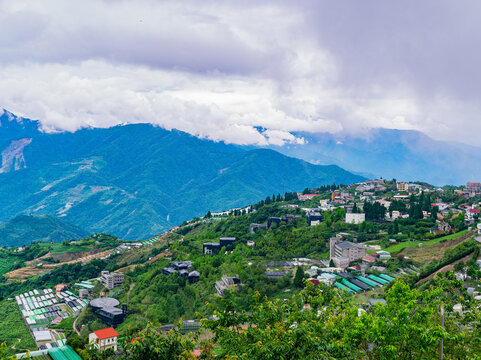 Hillside village and greenhouses nestled in misty mountains