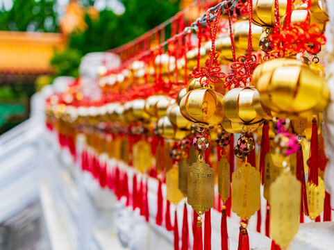 Golden prayer charms and red tassels hanging at a temple
