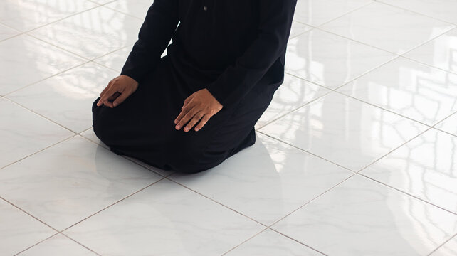Man Kneeling in Prayer on Tiled Floor in Mosque
