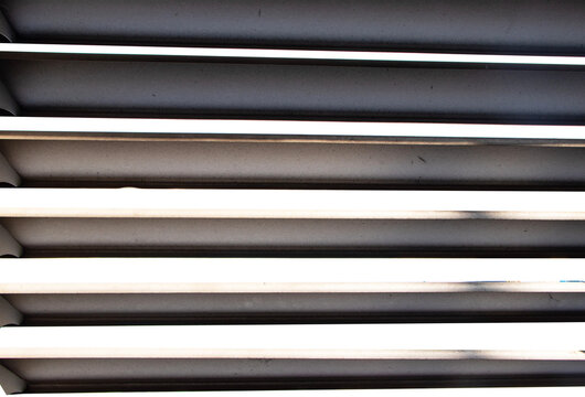 Modern metal ventilation louver with horizontal slats in black, white, and silver isolated on cut out PNG or transparent background. Clean geometric lines and repetitive pattern highlight functional.