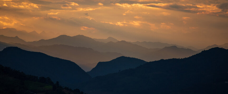 Banner Dramatic sunset mountain landscape. Dawn sky gold dusk time cloudscape with sunlight. Panorama Amazing Beautiful landscape hills with copy space. Banner Blue golden sky sunrise dramatic