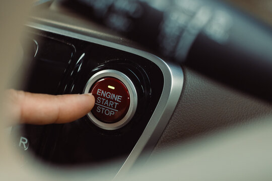 finger pressing the Engine start stop button of a car