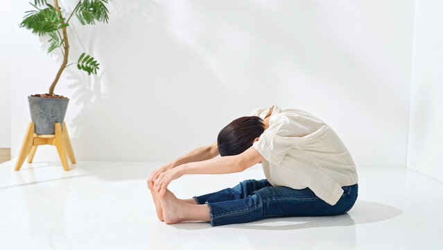 A middle-aged woman bending forward. Stretching, flexibility, gymnastics, softness, exercise, fitness, training, foot care