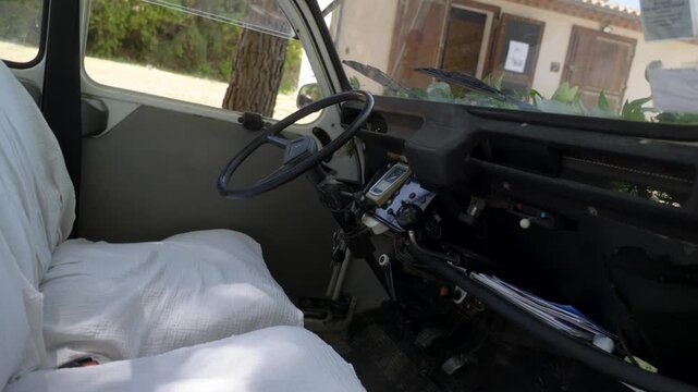 Interior view of a vintage car with white seat covers parked outdoors in daylight