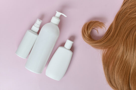 Hair care shampoo, conditioner and hair oil product bottles on light pink background