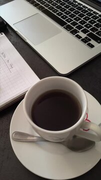 Vertical 4K video sequence of workspace with finance notebook, coffee cup, and laptop