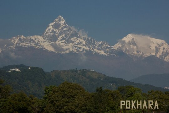 Snow capped Machapuchare Fishtail peak and Annapurna massif above green hills near the city of Pokhara, Nepal