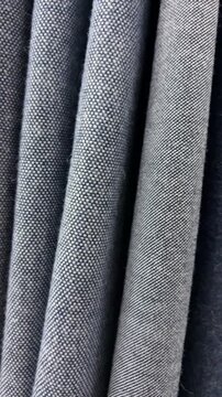 Vertical orientation slow motion close up shot of various blue plaid and textured tweed fabrics moving horizontally