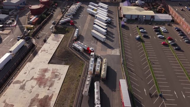 Aerial view of trucks, trailers and tanker vehicles positioned around an industrial loading and unloading area in England, showing logistics operations, freight transport and distribution infrastructu