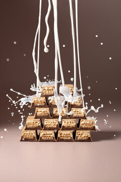 Dynamic milk splash on chocolate wafer bars on beige background